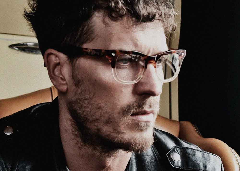 Man wearing vintage glasses and a leather jacket with a blurred background