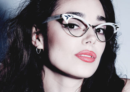 Close-up of a person wearing stylish vintage inspired white cat eye glasses with a dark background