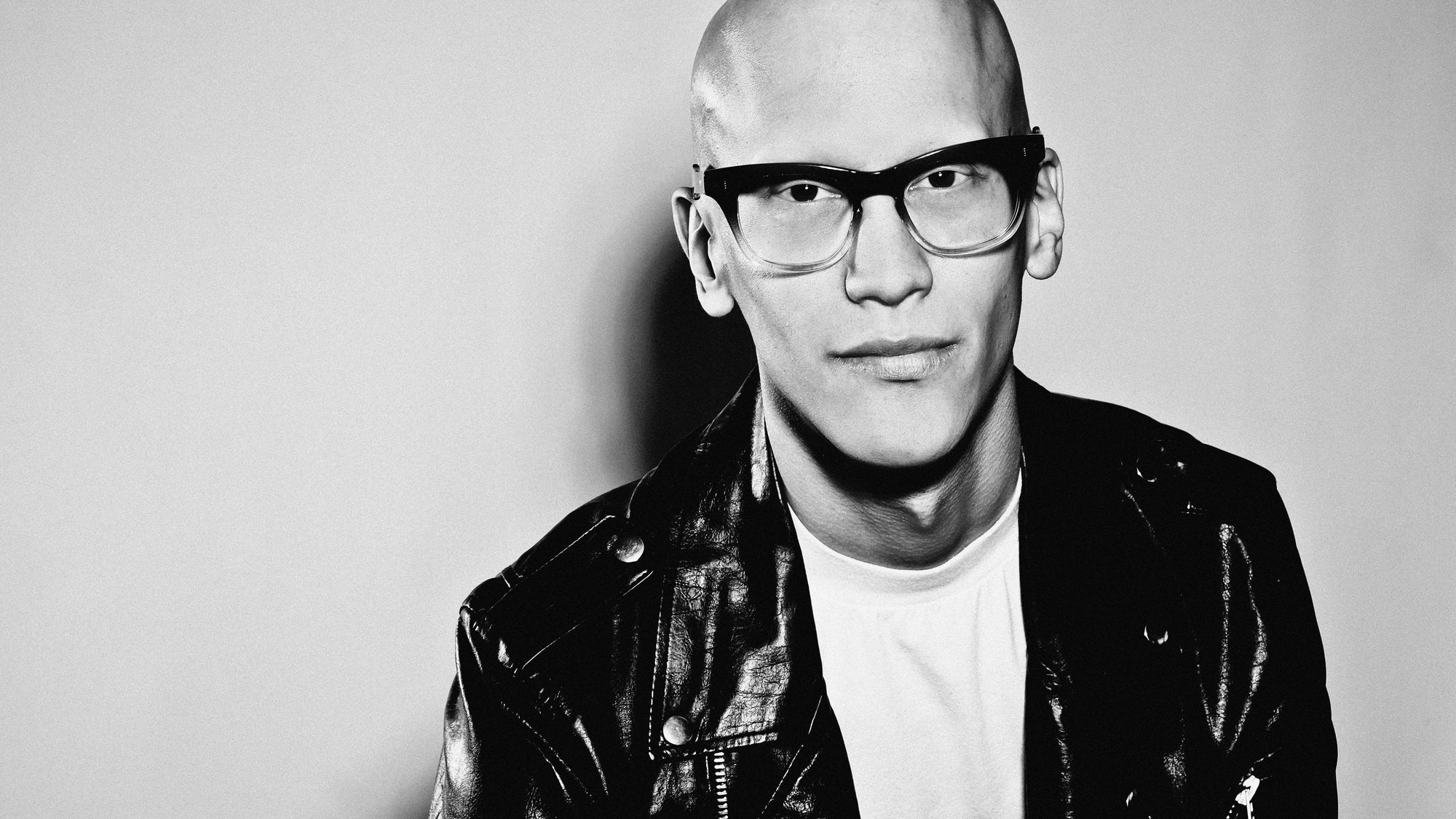 Black and white portrait of a person wearing wayfarer glasses and a leather jacket.